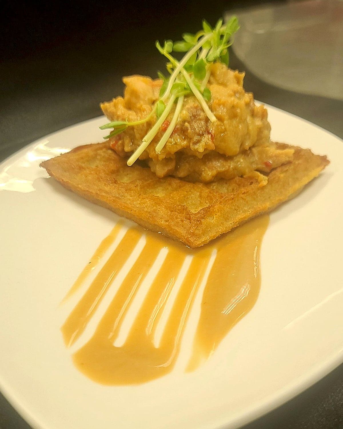 Chicken over a potato waffle, plated for service