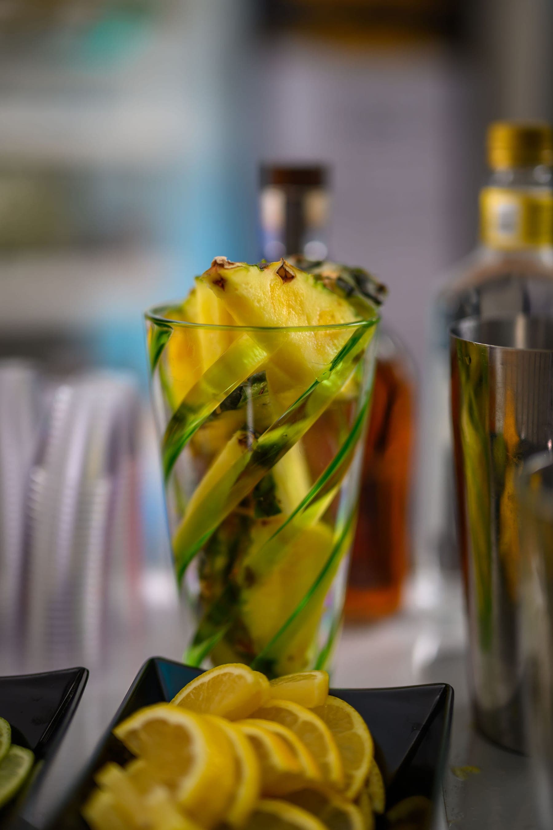 A tall drink garnished with pineapple, the bar behind it out of focus