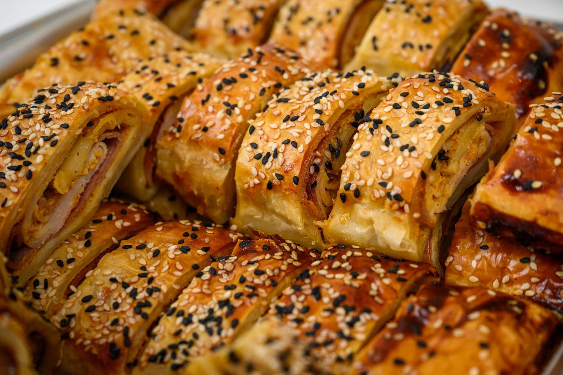 Franks in blankets in rows, sesame and poppy seeds on the pastry