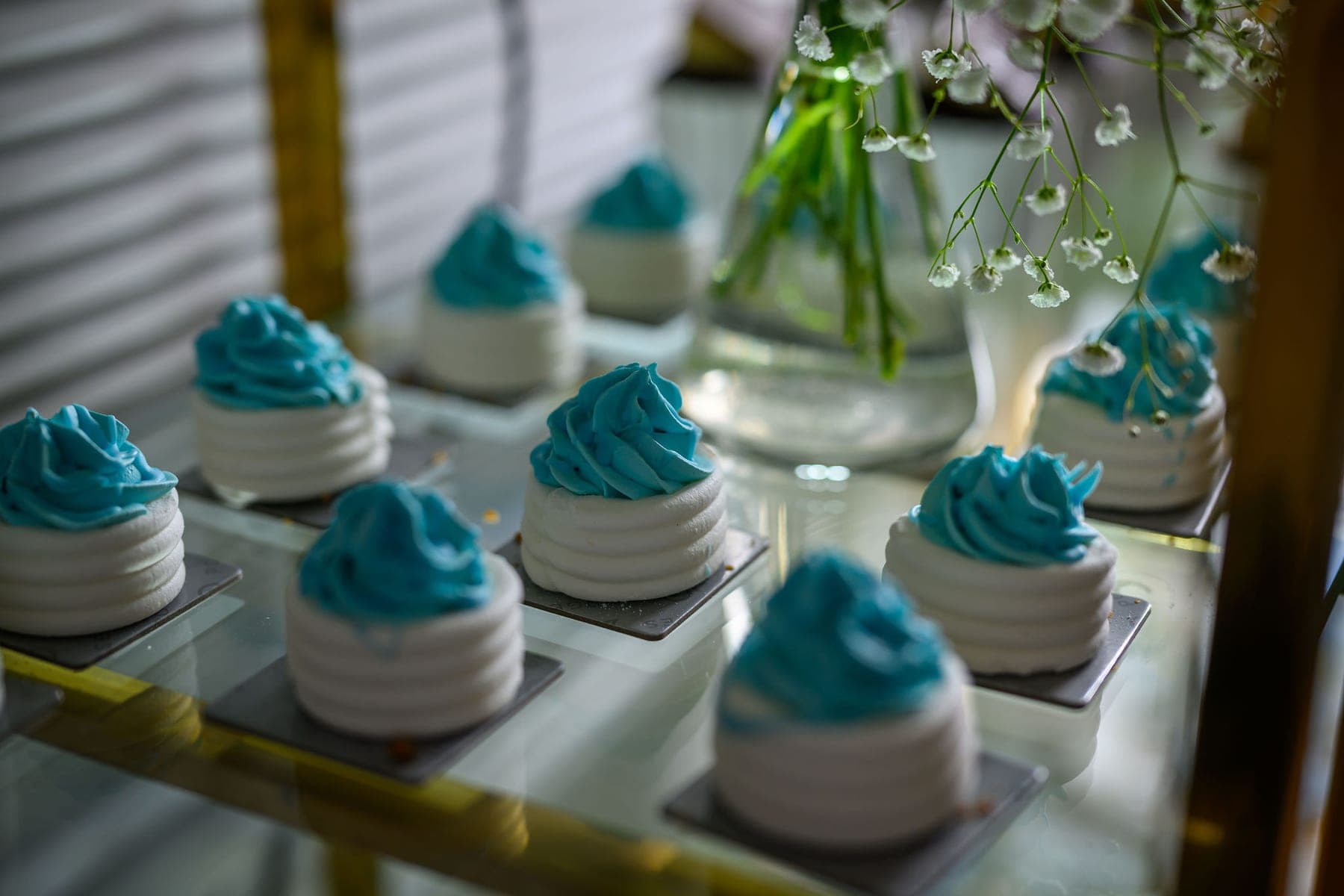 Meringues topped in blue on a gold-edged shelf