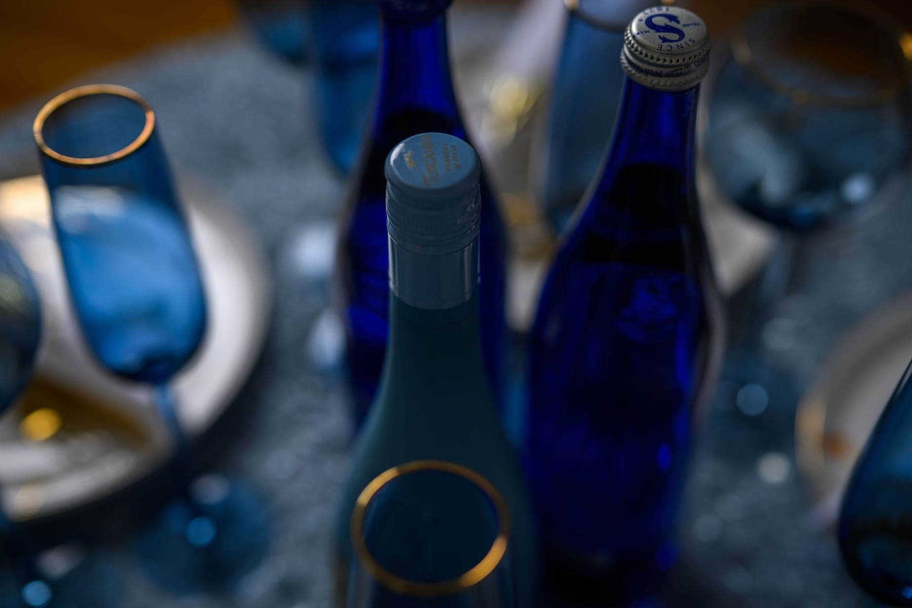 Cobalt glass bottles and stemware on a table dressed in crushed ice